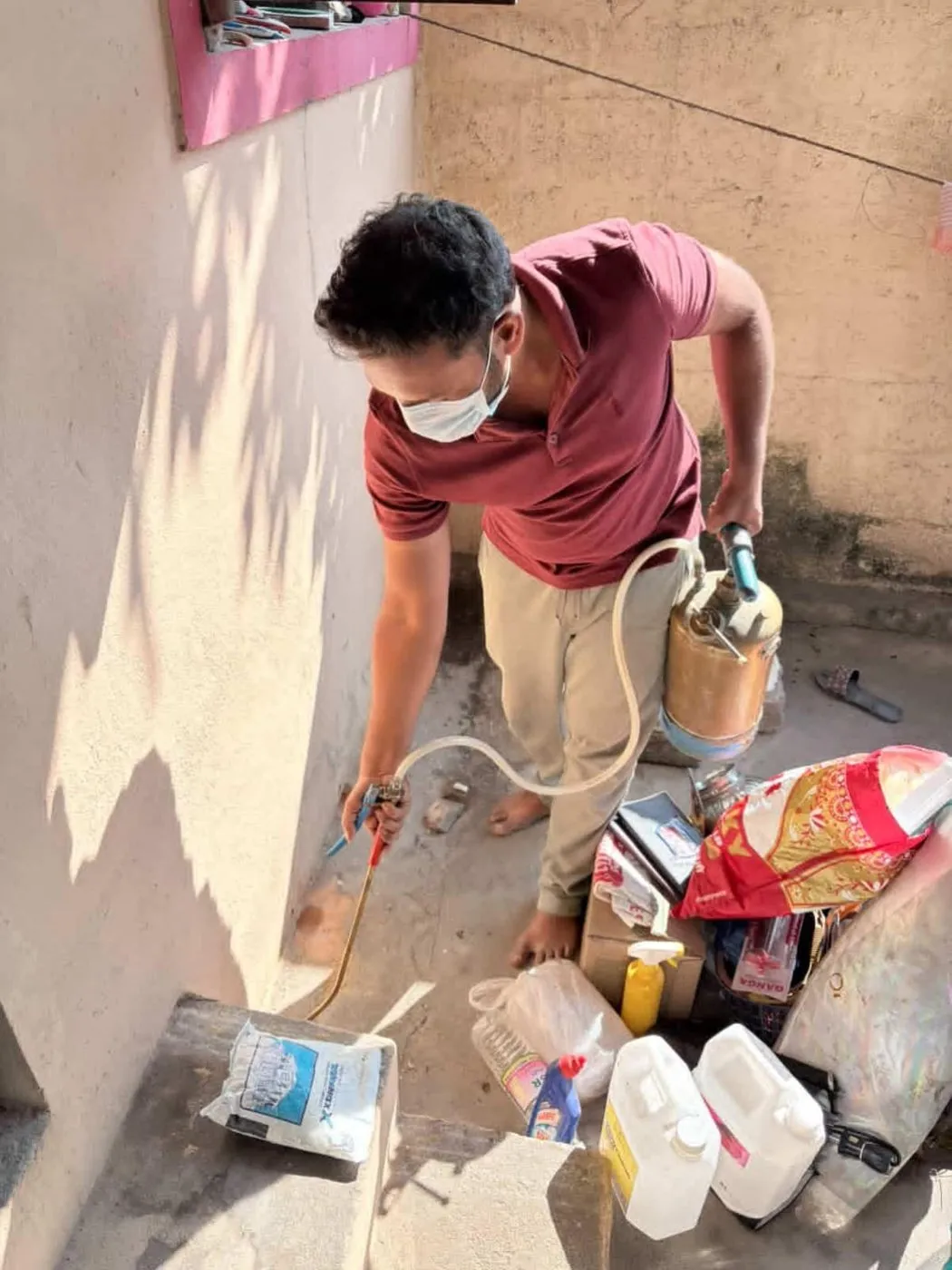 Pest control technician spraying a balcony and wall base