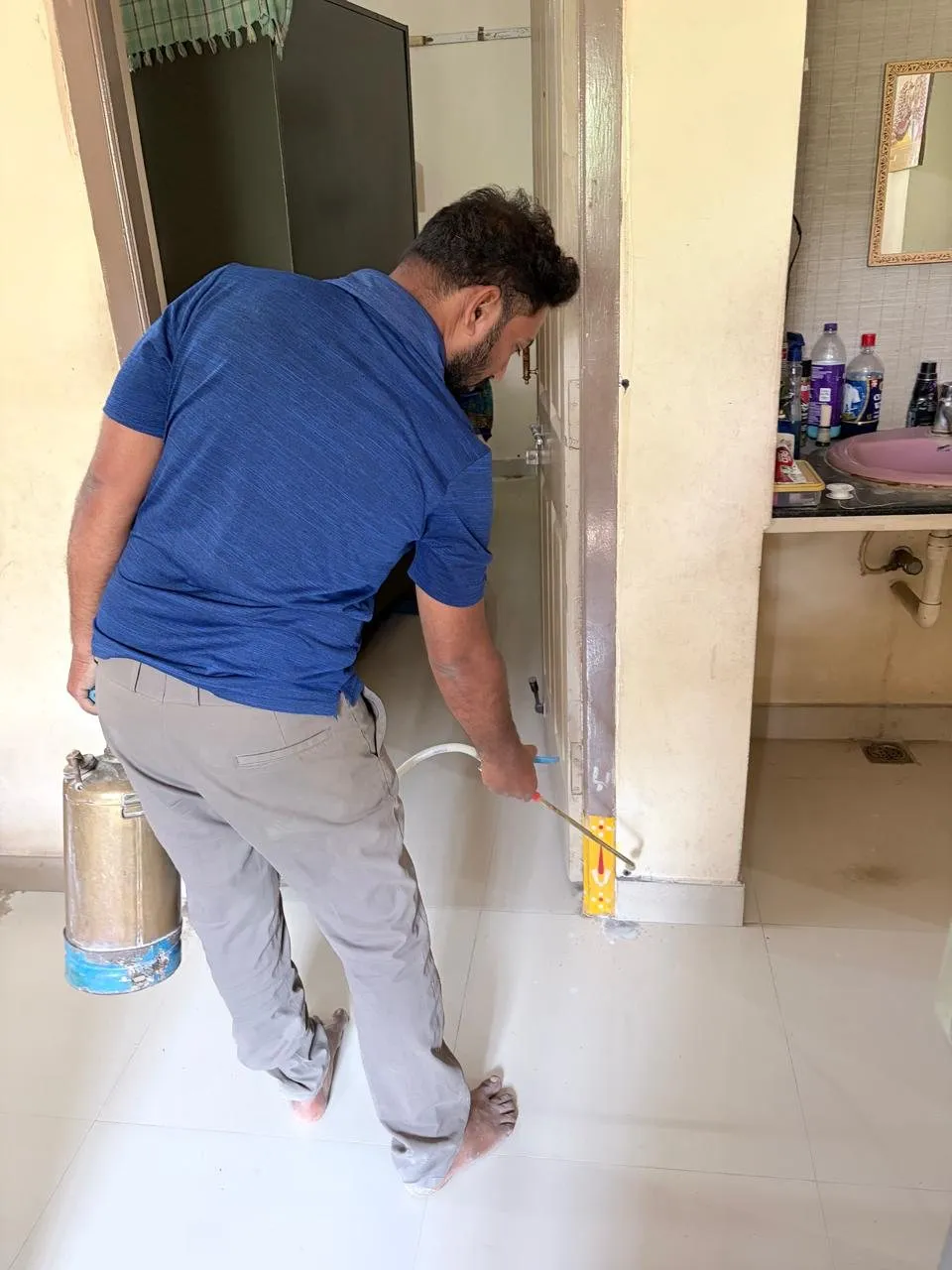 Technician treating skirting and wall base inside a house