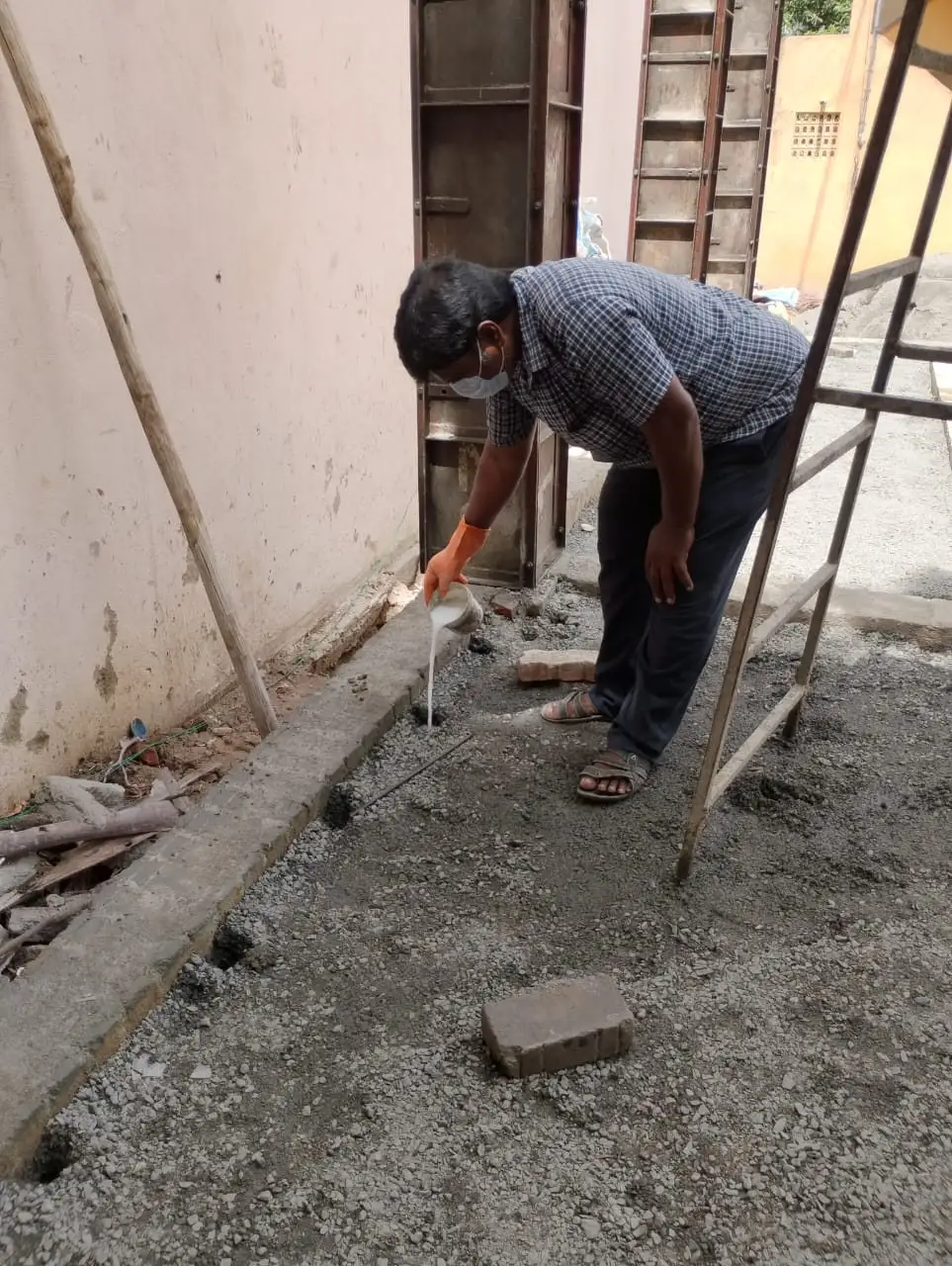 Technician applying anti-termite treatment along a building foundation