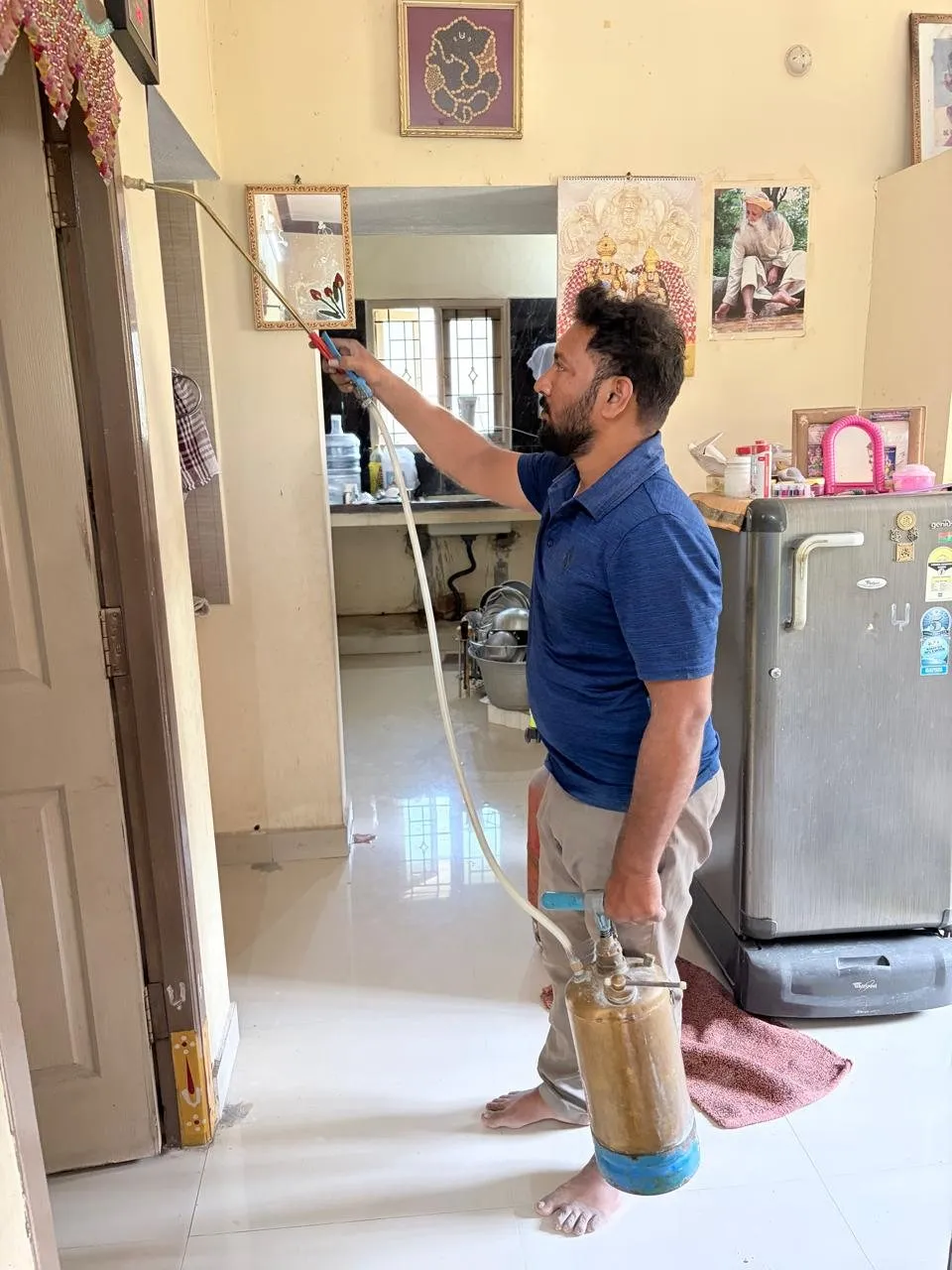 Pest control technician treating a wall inside a home